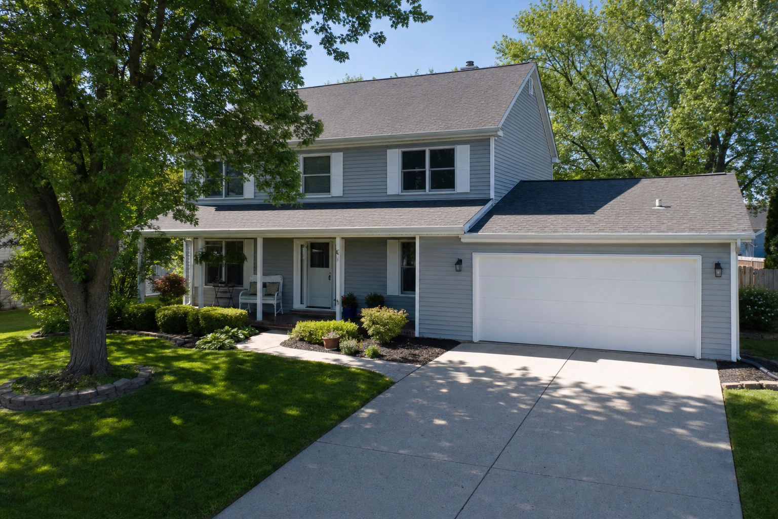 realistic attic and roofline inspection photo from outside a modest Waukegan Colonial home, visible soffit and roof ridge, light gray vinyl siding, mature trees, using visual directives: "modest front lawns with mature trees," "attached two-car garage, paved or concrete driveway," and "Inspection / drone footage" as a technical inspection mood, calm documentary style, no text on image