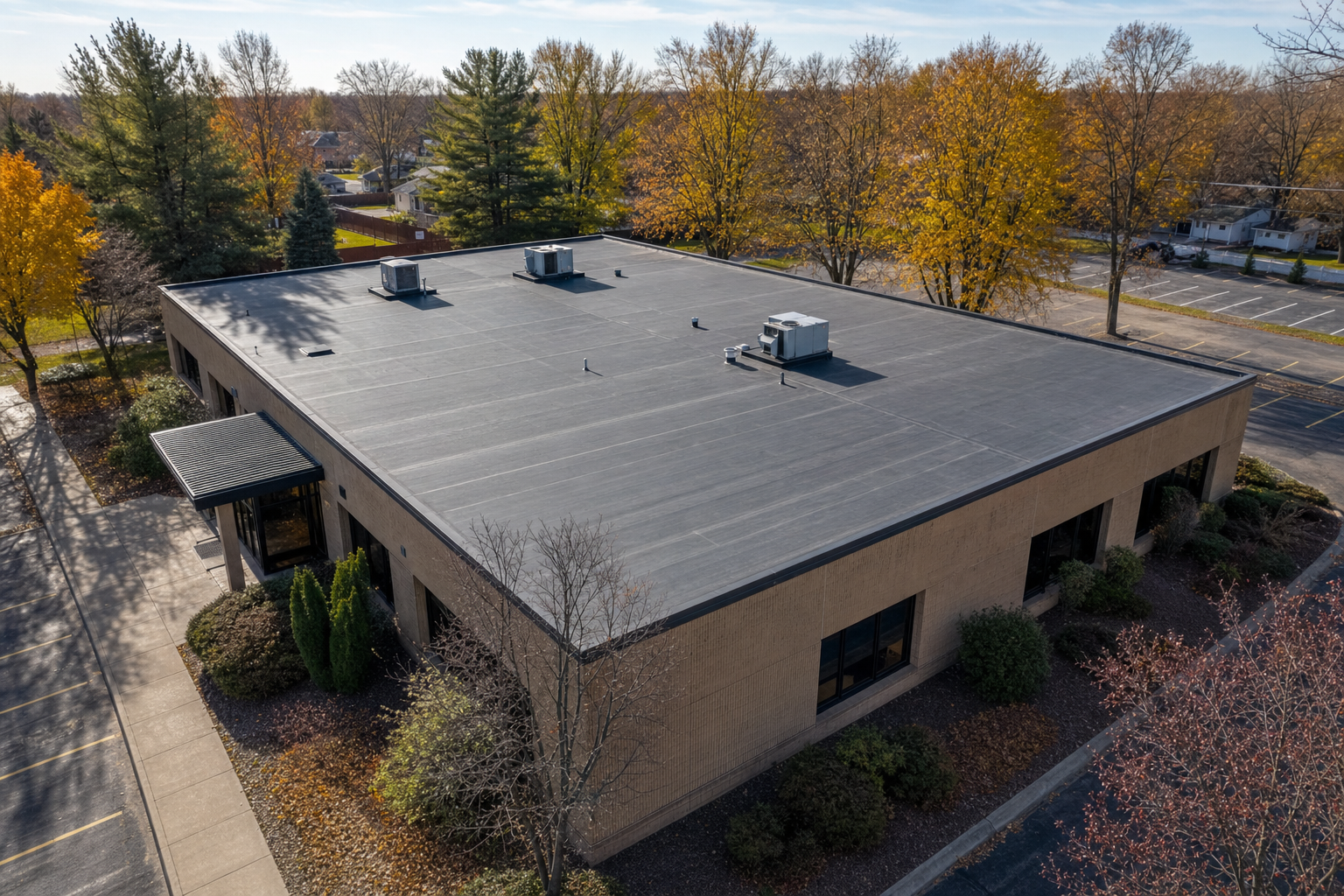 45-degree drone-style photo of a modest Lake County commercial building with a clean low-slope roof, mature trees nearby, late fall light, safe empty roof surface, no visible logos, no text